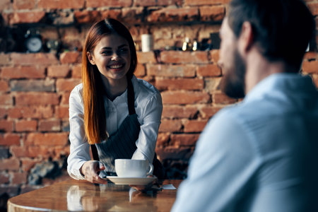 pretty woman waiter brings coffee service brick wallの写真素材