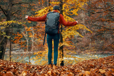 woman in a sweater and jeans and boots in autumn in a park in nature near the river