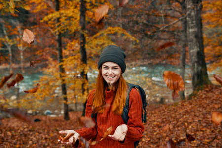 cheerful woman travels in the autumn forest in nature near the river and tall trees in the backgroundの写真素材