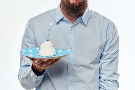 A man with a cake plate and in a blue shirt on a light background birthday party corporate capの写真素材