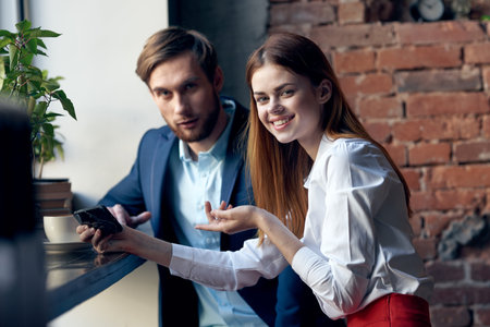 work colleagues man and woman sitting in a cafe with telephone communicationの写真素材