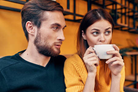 portrait of a man in a sweater and a woman with a cup of coffee interior roomの写真素材