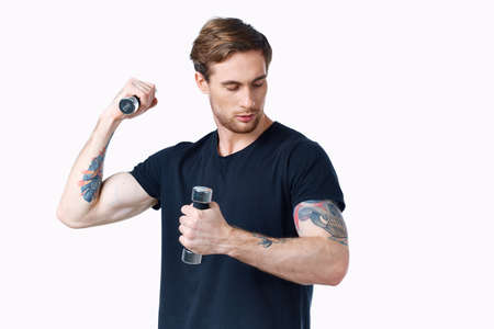 athlete in a black t-shirt with dumbbells on a white background side view