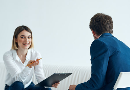 A man in a suit sits on a chair and a woman on a sofa psychologist communicatingの写真素材