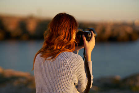 woman taking pictures on camera sea in mountains back view