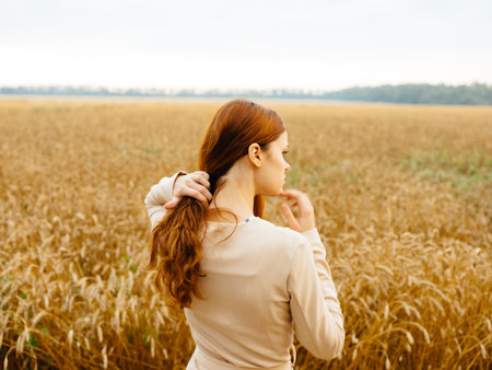 woman near dry fields in nature in a sundress and red hairの写真素材