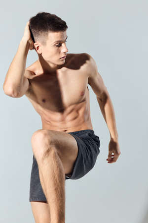 athlete in shorts doing exercise leaning forward on gray backgroundの写真素材