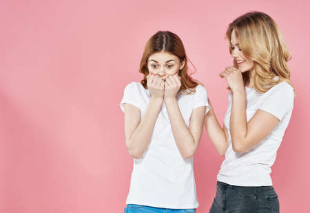 Cheerful women in white T-shirts hugs socializing lifestyle Glamor pink background