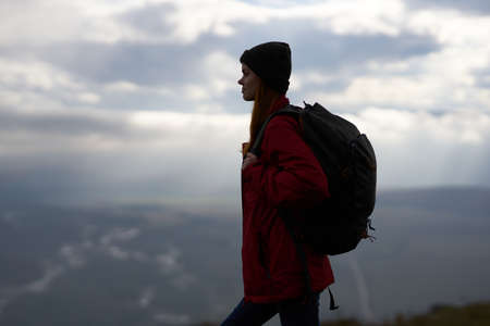 woman travels in the mountains with a backpack in the evening landscape clouds weather