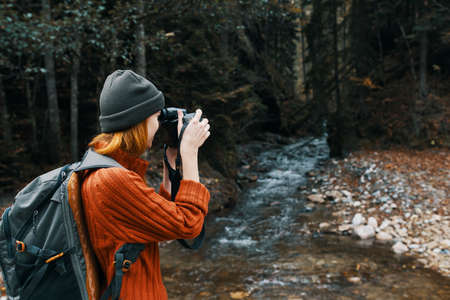 woman with a camera on nature in the mountains near the river side viewの写真素材