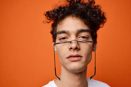 guy in a white t-shirt glasses close-up orange backgroundの写真素材