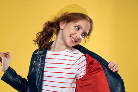 Cheerful little girl in sunglasses and hat lifestyle studio yellow background fashionの写真素材