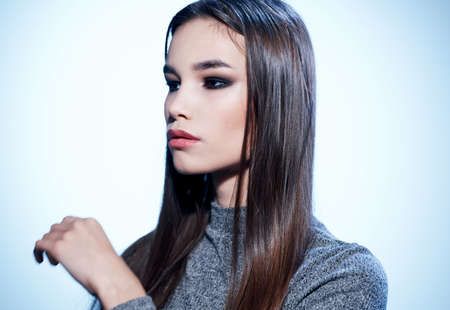 Portrait of a charming brunette in a gray sweater close-up of the shadow on the eyelids