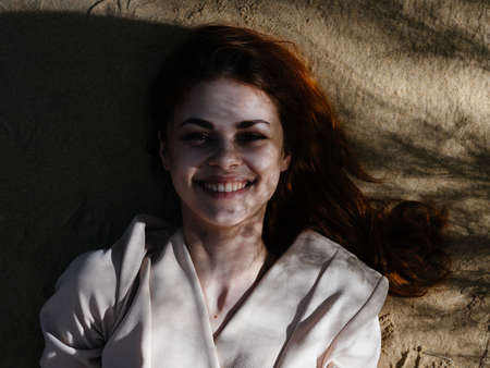 Cheerful woman lies on the ground smile resting fresh air natureの写真素材