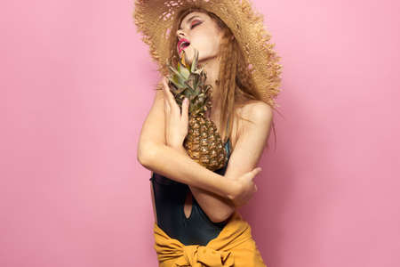 woman in beach hat pineapple exotic swimsuit pink backgroundの写真素材