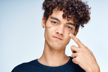 handsome guy with curly hair applies a black mask on his face cosmetologyの写真素材