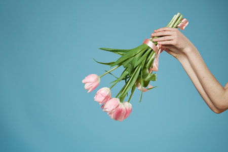 Bouquet in woman hands with gift holiday Valentine Day blue backgroundの写真素材