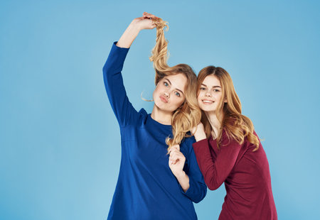 two women in dresses hugs lifestyle blue backgroundの写真素材