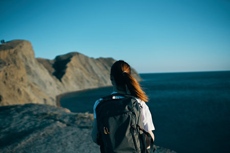 woman with backpack in the mountains in nature back view