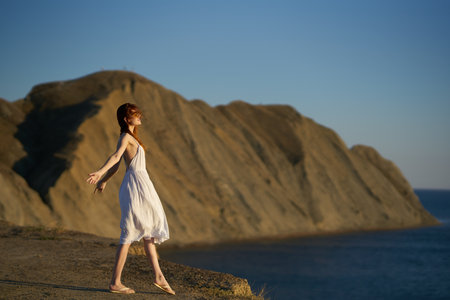 a traveler in a white dress walks in nature in the mountains near the sea
