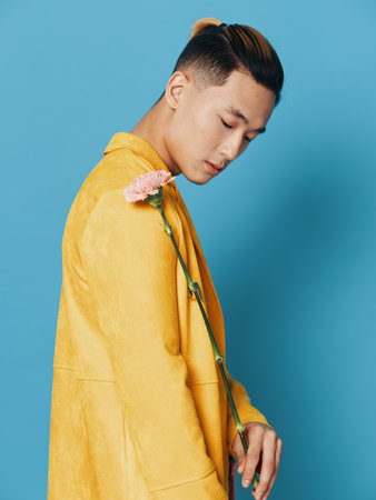 Side view of a sexy guy with a flower on a blue background and a yellow coatの写真素材