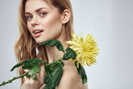 Portrait of a beautiful woman with a yellow flower on a light background charming smile model red hairの写真素材