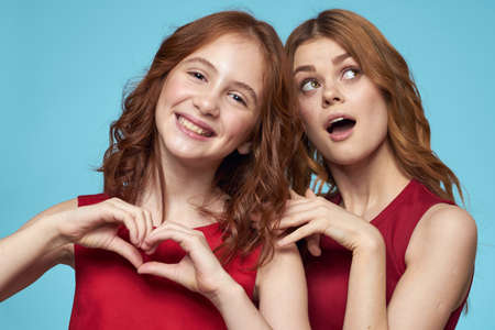 Cheerful mom and daughter hugs joy lifestyle communication friendship blue backgroundの写真素材