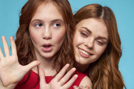 Cheerful mom and daughter hugs joy lifestyle communication friendship blue backgroundの写真素材