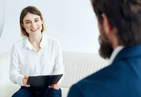 Woman with documents and a man in a suit are sitting on the couch recruiting vacancy resume