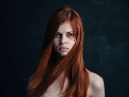 Portrait of a woman with red hair on a black background naked shoulders modelの写真素材