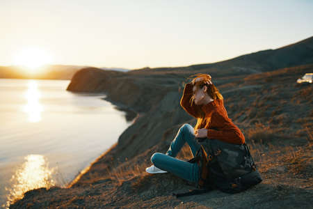 woman tourist sitting on the ground admiring nature landscape fresh airの写真素材