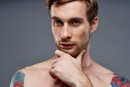 portrait of young man with tattoos on gray background and beautiful face model cropped viewの写真素材