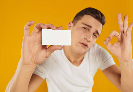 guy with a white card on a yellow background Copy Space mockupの写真素材