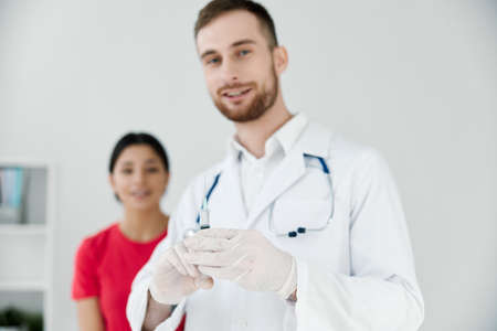 male doctor in white coat female patient in the background