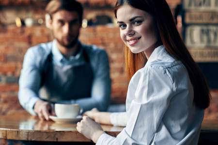 happy woman with cup of coffee and man bartender in apronの写真素材