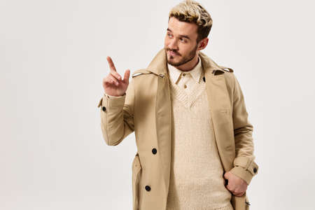 handsome man gesturing with hand beige coat modern style cropped viewの写真素材