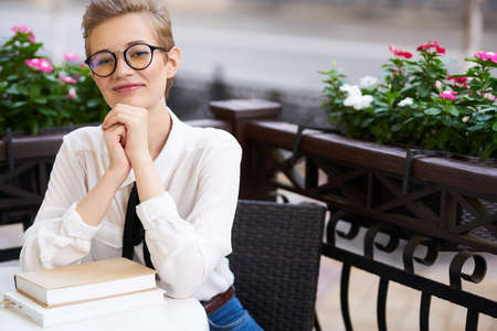 woman in shirt and tie at the table book education interior flowersの写真素材