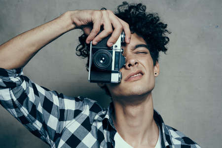 handsome guy with a camera near his face and curly hair plaid shirt hobby photographerの写真素材
