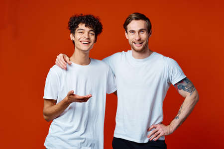 Two cheerful friends in white t-shirts stand side by sideの写真素材