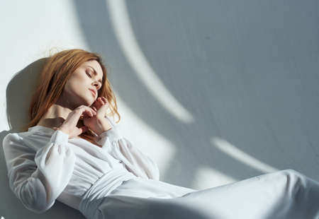 Romantic woman model leaning against the wall indoors and falling shadow