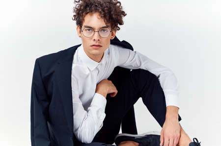 a guy in a classic suit and glasses sits on the floor In a bright roomの写真素材