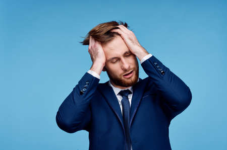 business man in a suit holds his hand on his head emotion financialの写真素材