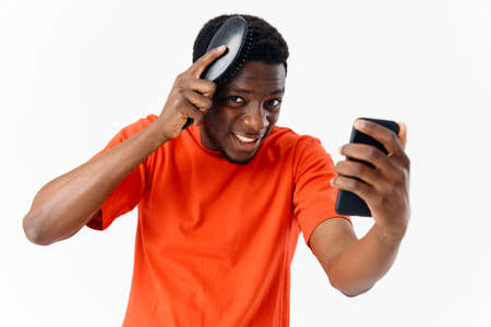 man combing his head african appearance phone in hand