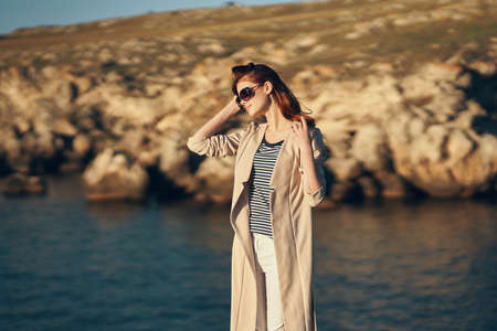 attractive woman in sunglasses gesturing with hands on nature in the mountains near the riverの写真素材