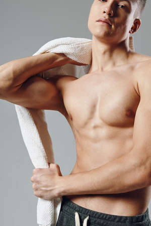 sporty man on muscular torso towels in hands cropped view gray backgroundの写真素材