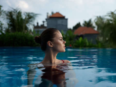 woman with bare shoulders in clear pool water side view model portrait