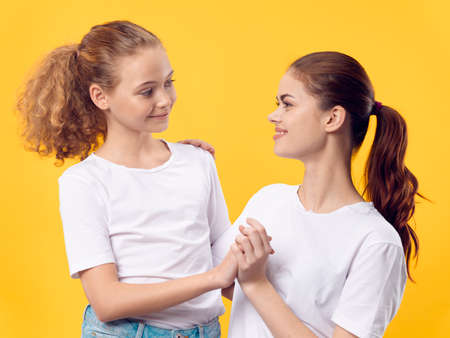 little girl and young mother look at each other on a yellow background familyの写真素材
