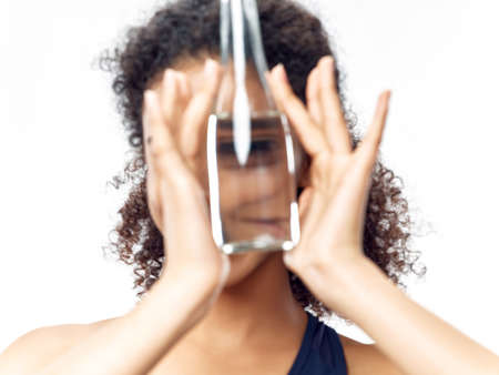 women with a bottle of water in their hands in front of the face on a light background