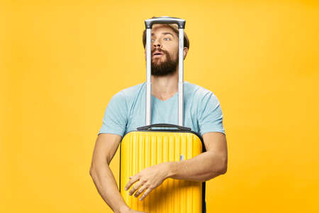 traveler hugs yellow suitcase on isolated background and iron handle pushed up