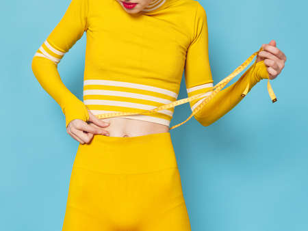 slender woman measures her figure with a tape workout tracksuits